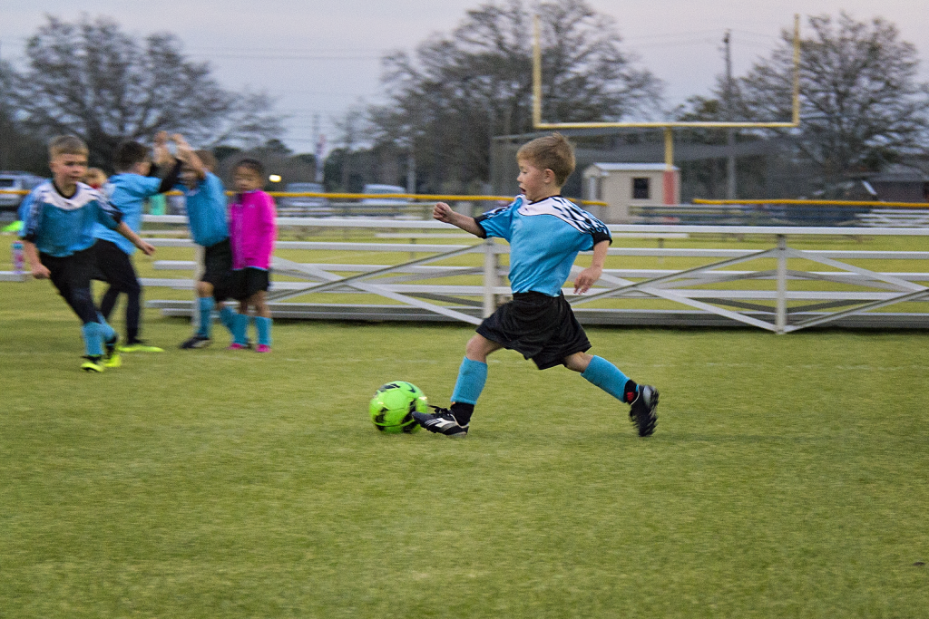 A young boy is shown kicking a soccer ball while running