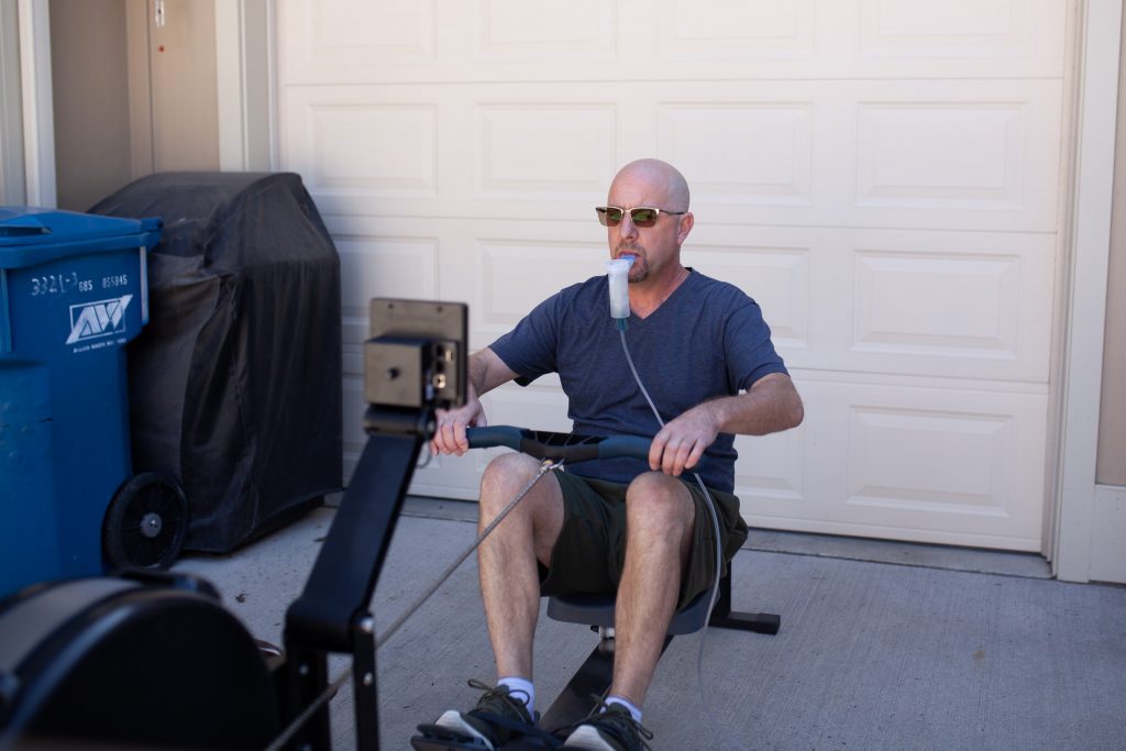Man using a breathing device while using a rowing machine.